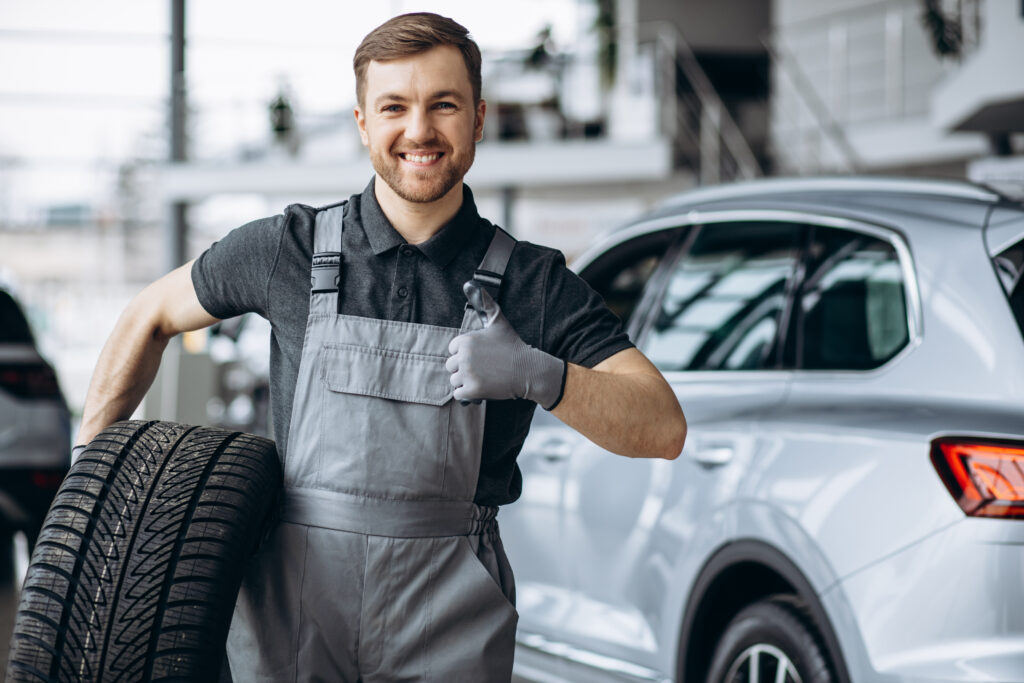 Workman At Car Repair Shop Changing Tires